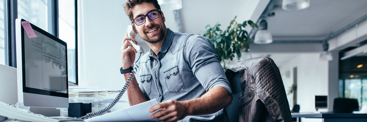 Foto: Ausbilder spricht am Festnetztelefon im Büro.