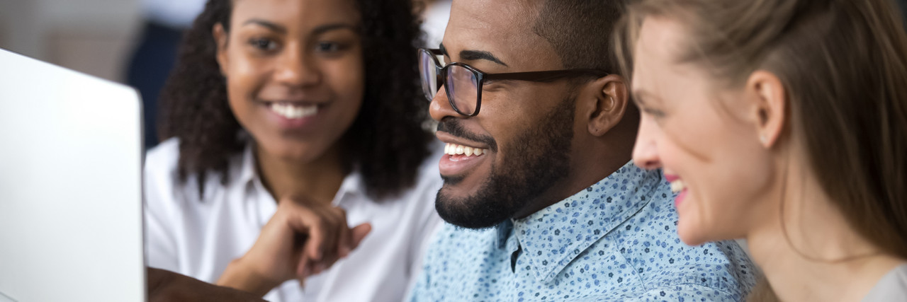 Foto: ein multiethnisches Team aus einem Mann und zwei Frauen arbeitet gemeinsam am PC. 