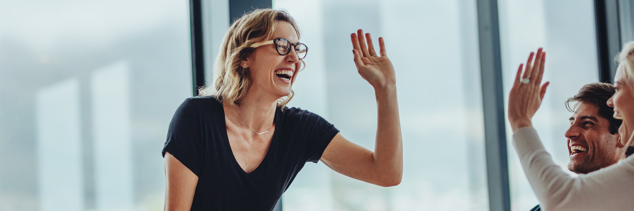 Foto: zwei Frauen geben sich ein High-Five in einem Meeting.