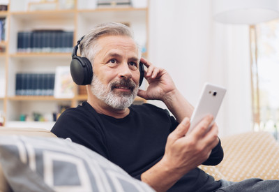 Foto: Mann mittleren Alters h&ouml;rt Musik oder Podcast &uuml;ber Kopfh&ouml;rer.