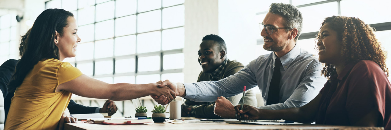 Foto: Mann und Frau geben sich bei einem Meeting die Hand.