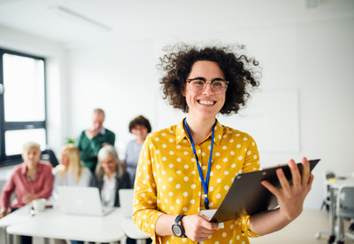 Portrait of teacher with seniors attending computer and technology education class.