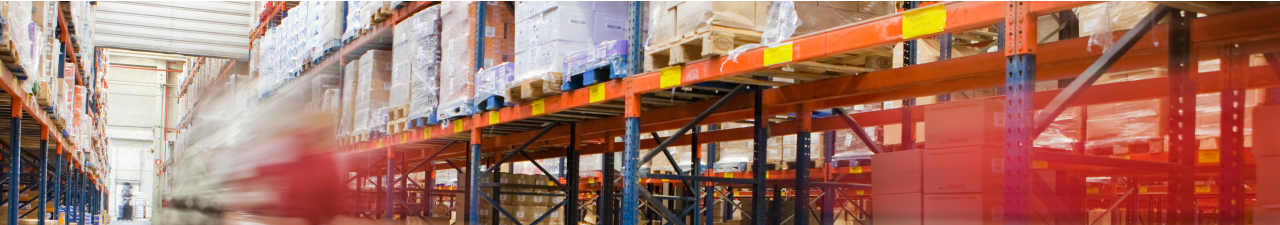 Foto: eine Lagerhalle mit hohen Regalen. Mittig f&auml;hrt ein Gabelstapler.