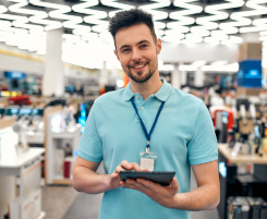 Foto: ein Verkäufer und Ausbilder in einem Elektronik-Handel. In der Hand hält er ein Tablet.