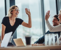 Foto: eine lächelnde Ausbilderin oder Lehrerin hat die Hand in der Luft um der Kollegin ein High-Five zu geben. 